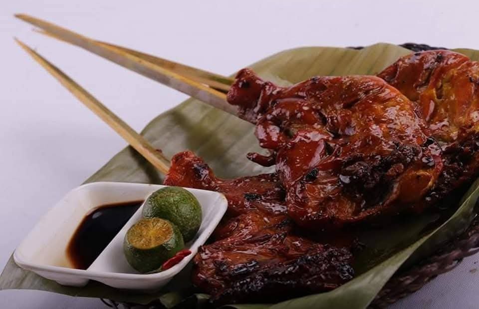 Grilled chicken inasal on a banana leaf with calamansi and a soy-vinegar dipping sauce